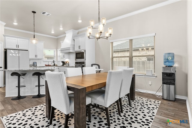 dining space featuring a chandelier, ornamental molding, and sink