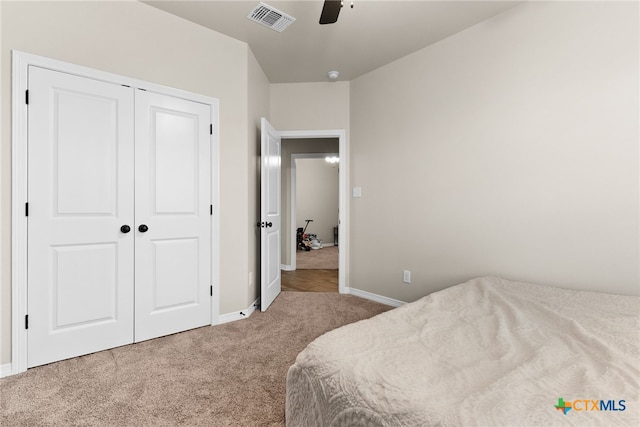 bedroom with ceiling fan, light carpet, and a closet