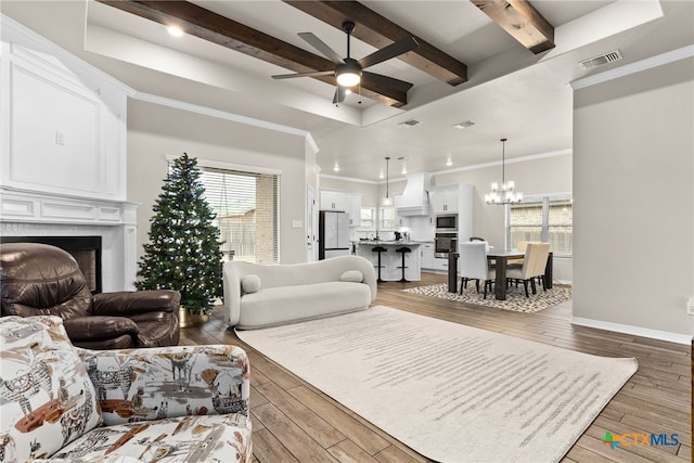 living room featuring a high end fireplace, ornamental molding, ceiling fan with notable chandelier, and hardwood / wood-style flooring