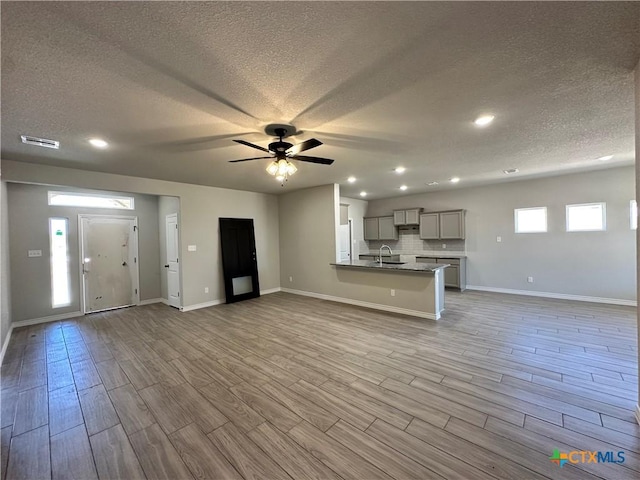kitchen featuring open floor plan, gray cabinets, a textured ceiling, wood finished floors, and a ceiling fan