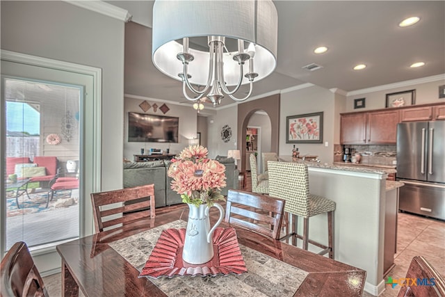 dining room with crown molding, light tile patterned floors, and a chandelier