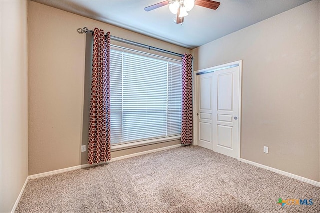 carpeted spare room featuring ceiling fan