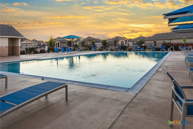 pool at dusk featuring a patio