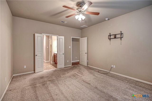 unfurnished bedroom featuring connected bathroom, light colored carpet, and ceiling fan