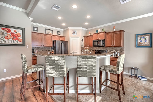 kitchen with backsplash, stainless steel appliances, a breakfast bar area, and an island with sink