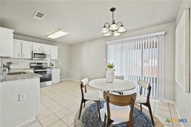 dining room with sink, light tile patterned floors, and an inviting chandelier