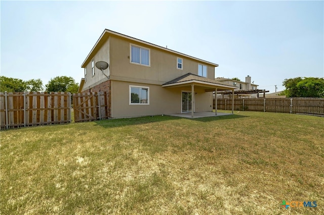 back of property with a lawn and a patio area