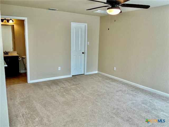 unfurnished bedroom featuring sink, ensuite bath, light colored carpet, and ceiling fan