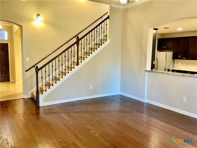 unfurnished living room featuring dark wood-type flooring and ornamental molding