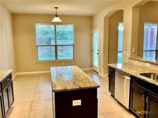 kitchen featuring dishwasher, a kitchen island, light stone counters, and decorative light fixtures