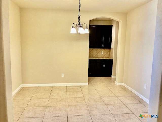 unfurnished dining area with a notable chandelier and light tile patterned floors