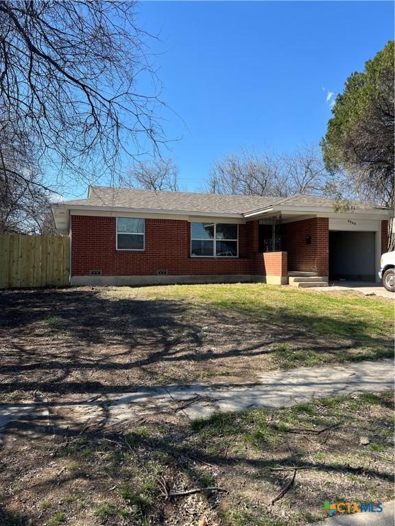 ranch-style home with brick siding, fence, driveway, and an attached garage