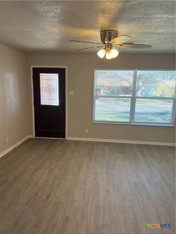 foyer entrance featuring a textured ceiling, baseboards, and wood finished floors