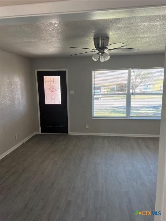 foyer entrance with a textured ceiling, baseboards, and dark wood-type flooring