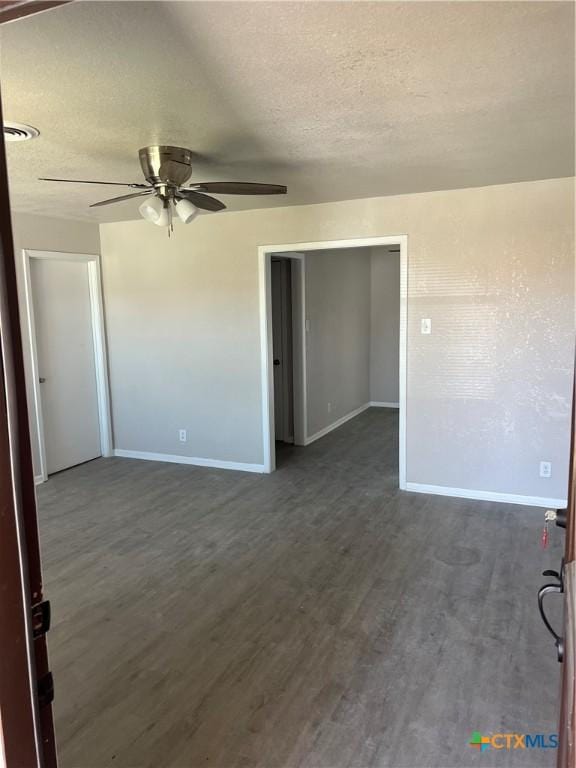 spare room with dark wood-type flooring, a textured ceiling, and baseboards