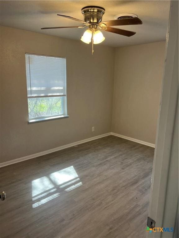 empty room with a ceiling fan, baseboards, and wood finished floors