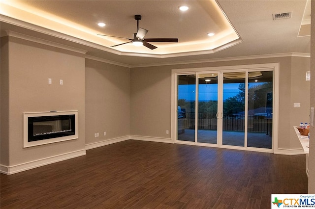 unfurnished room featuring ceiling fan, a raised ceiling, dark hardwood / wood-style flooring, and ornamental molding