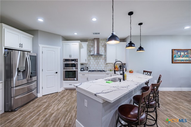 200 Wood Cv, Georgetown, TX 78633 - kitchen with appliances with stainless steel finishes, wall chimney range hood, a sink, light wood-style flooring, and recessed lighting