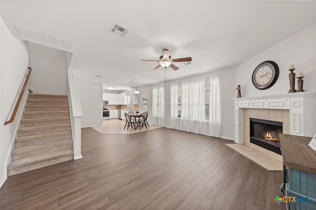 unfurnished living room with dark hardwood / wood-style flooring, ceiling fan, and a tile fireplace