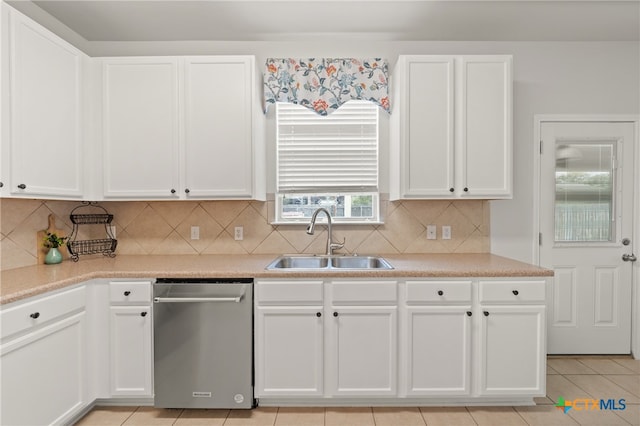 kitchen featuring stainless steel dishwasher, white cabinets, sink, and light tile patterned floors