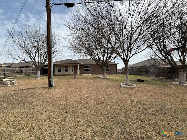 exterior space featuring a front yard, fence, and brick siding