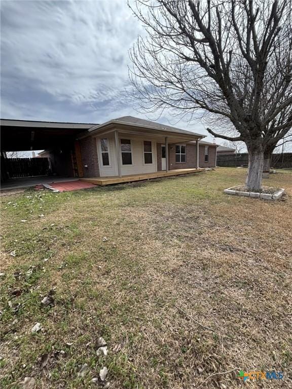 exterior space featuring brick siding, a lawn, and fence