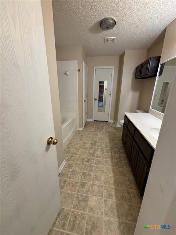 full bath featuring visible vents, baseboards, vanity, bathing tub / shower combination, and a textured ceiling