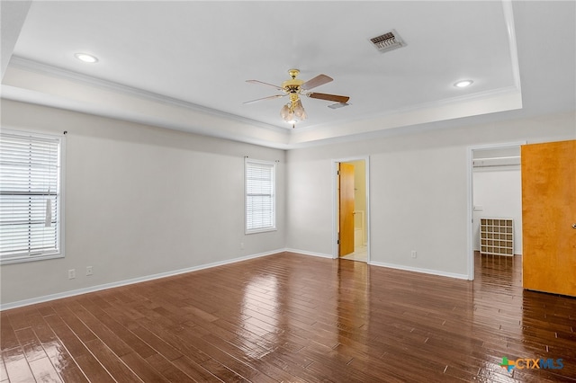 unfurnished room featuring ornamental molding, dark hardwood / wood-style flooring, ceiling fan, and a raised ceiling