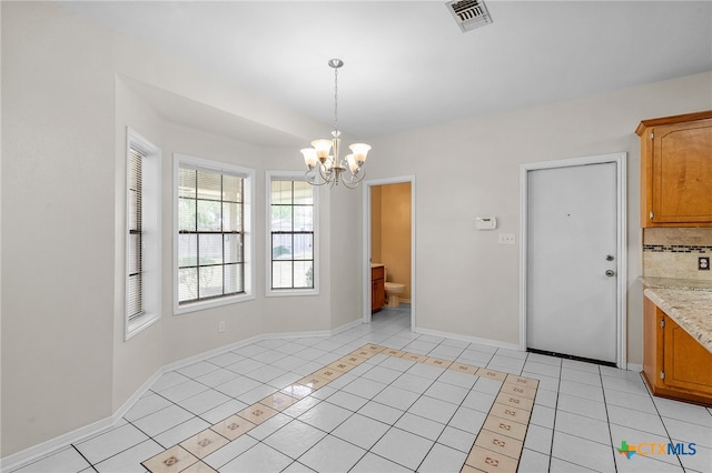 unfurnished dining area with an inviting chandelier and light tile patterned floors