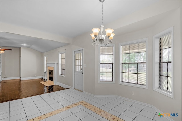 interior space with ceiling fan with notable chandelier, plenty of natural light, light tile patterned floors, and vaulted ceiling