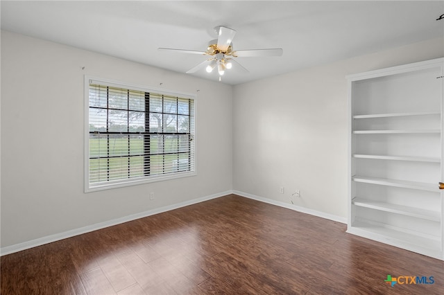 unfurnished room featuring dark wood-type flooring, ceiling fan, and built in shelves