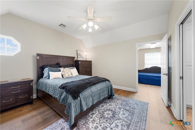 bedroom with vaulted ceiling, a ceiling fan, light wood-style flooring, baseboards, and visible vents