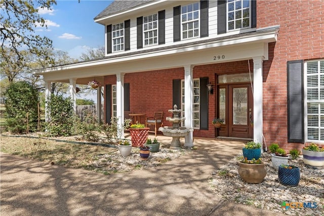property entrance with brick siding and covered porch
