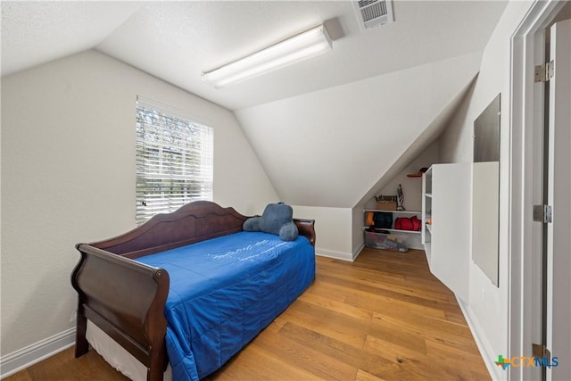 bedroom featuring vaulted ceiling, wood finished floors, and baseboards
