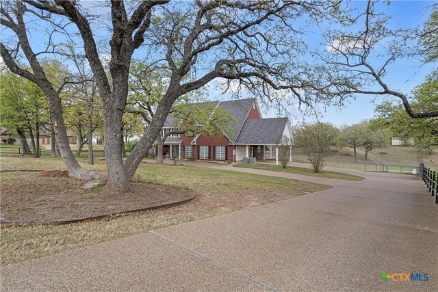 view of front of house with fence, a front lawn, and driveway