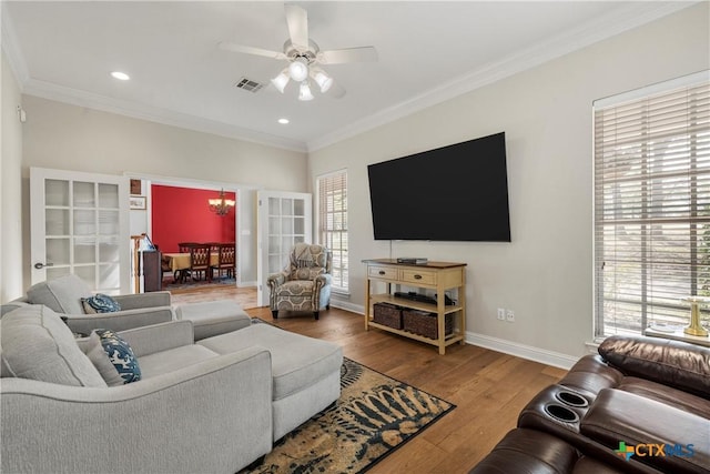 living area with ceiling fan with notable chandelier, visible vents, and ornamental molding