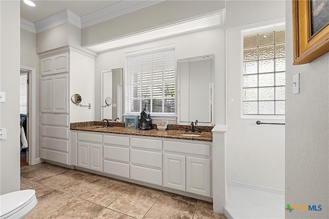 bathroom with ornamental molding, a sink, double vanity, and tile patterned floors