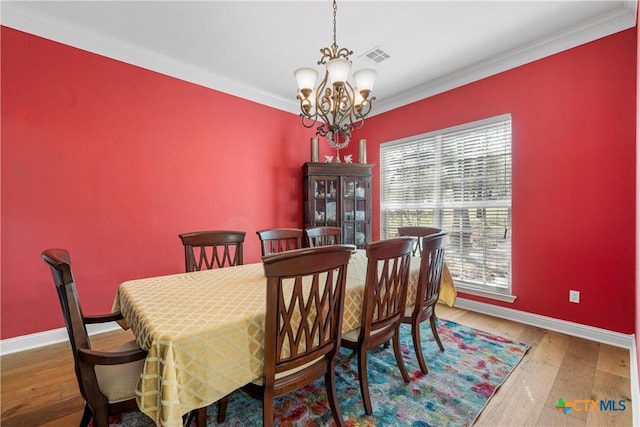 dining room with a notable chandelier, wood finished floors, baseboards, ornamental molding, and visible vents
