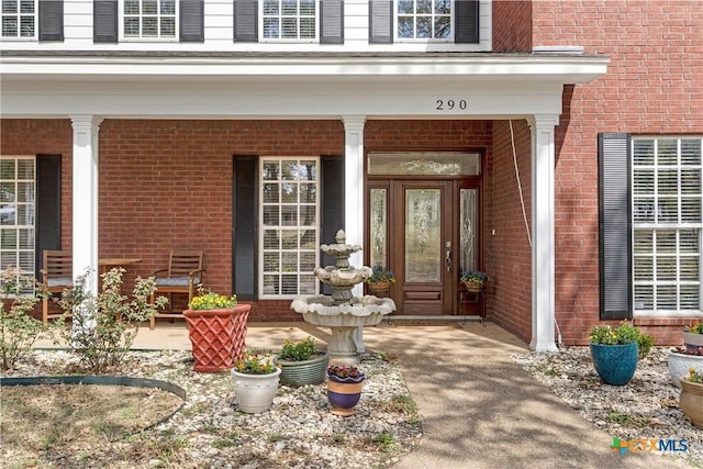 entrance to property featuring brick siding and a porch