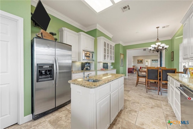kitchen with an island with sink, stainless steel appliances, white cabinetry, ornamental molding, and visible vents