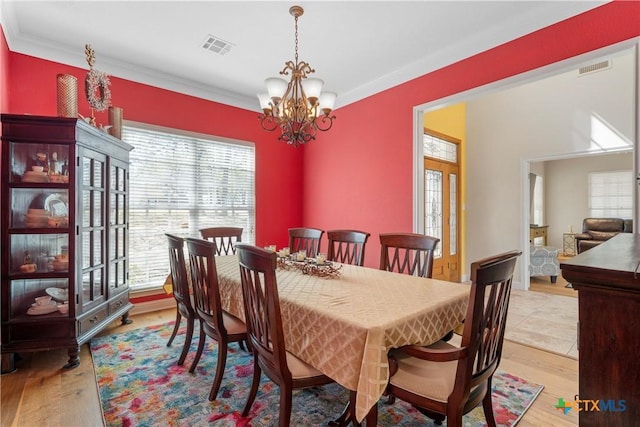 dining area with wood finished floors, a notable chandelier, and ornamental molding