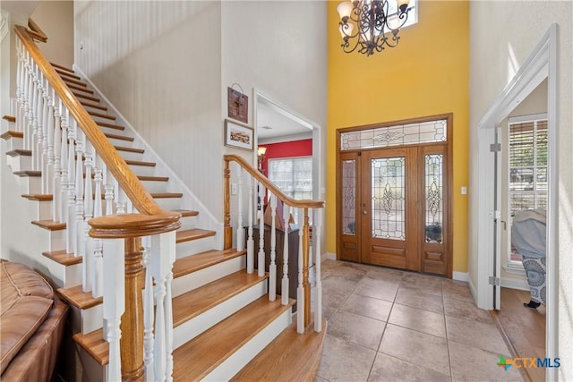 foyer entrance with stairway, a towering ceiling, and plenty of natural light