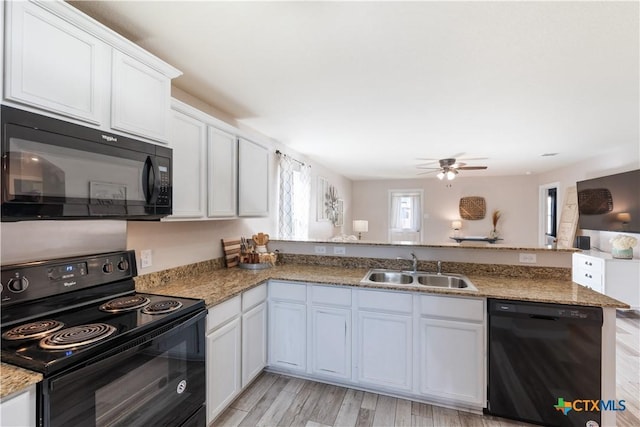 kitchen with kitchen peninsula, light wood-type flooring, sink, black appliances, and white cabinetry