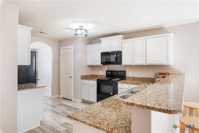 kitchen featuring kitchen peninsula, white cabinets, black appliances, and light wood-type flooring