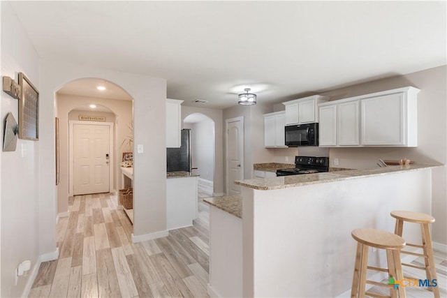 kitchen featuring black appliances, white cabinets, kitchen peninsula, and light wood-type flooring