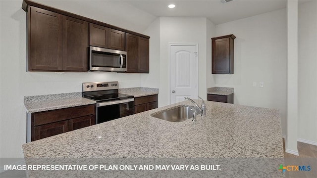 kitchen with dark brown cabinetry, sink, a center island with sink, appliances with stainless steel finishes, and light stone countertops