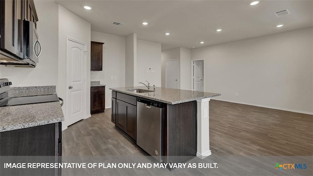 kitchen with an island with sink, sink, light stone counters, stainless steel appliances, and dark wood-type flooring