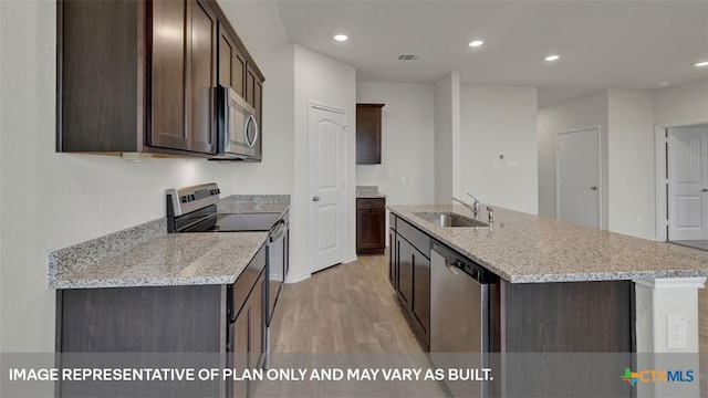 kitchen with dark brown cabinetry, appliances with stainless steel finishes, sink, and a center island with sink