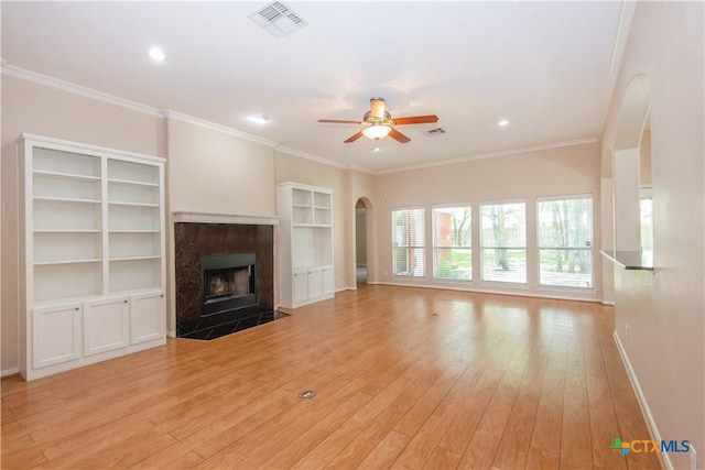 1935 Grandview Dr, Salado, TX 76571 - unfurnished living room with arched walkways, a ceiling fan, light wood-style flooring, a premium fireplace, and ornamental molding