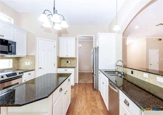 1935 Grandview Dr, Salado, TX 76571 - kitchen featuring appliances with stainless steel finishes, a chandelier, arched walkways, white cabinets, and decorative backsplash
